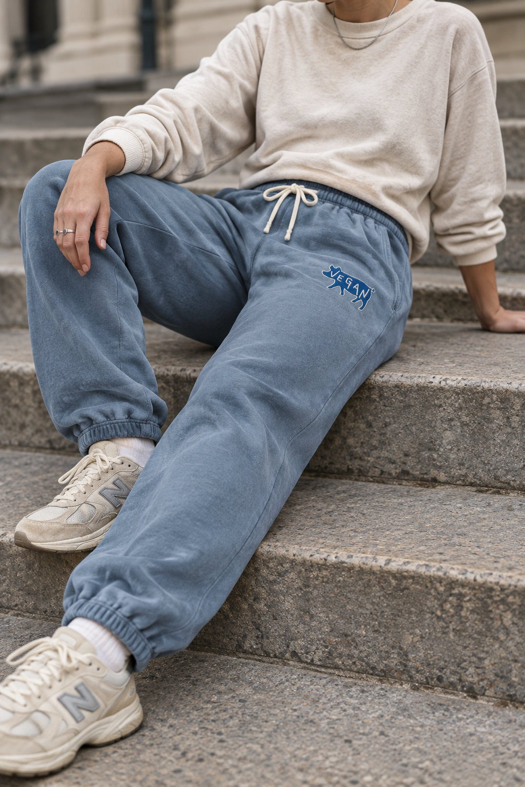 Model seated on city steps wearing Blue Jean vegan embroidered cotton sweatpants