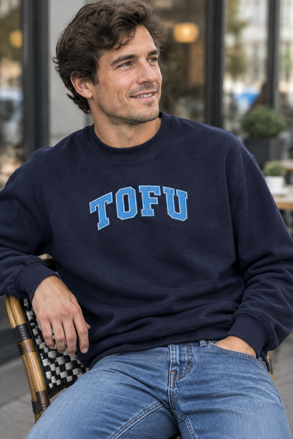 Model wearing J. Navy TOFU embroidered crewneck sweatshirt seated outside a café