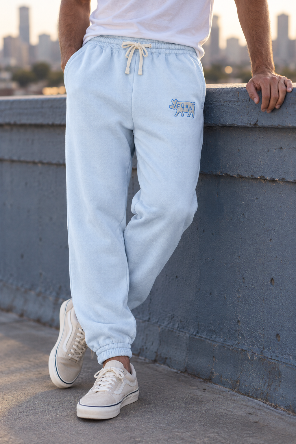 Model by rooftop rail wearing Hydrangea vegan embroidered cotton sweatpants